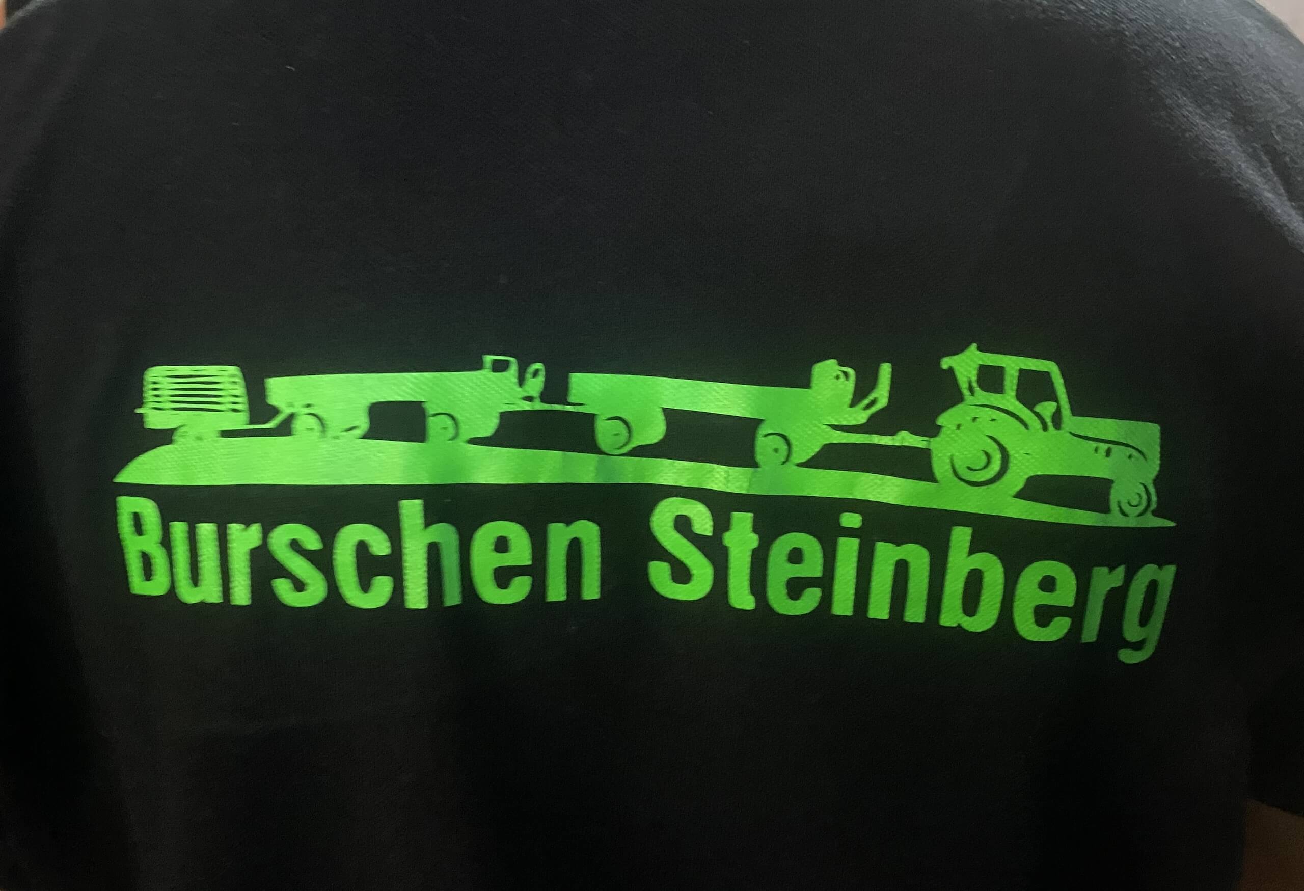 Grünes Logo von Burschen Steinberg mit Traktor- und Anhängerdesign auf schwarzem Hintergrund.