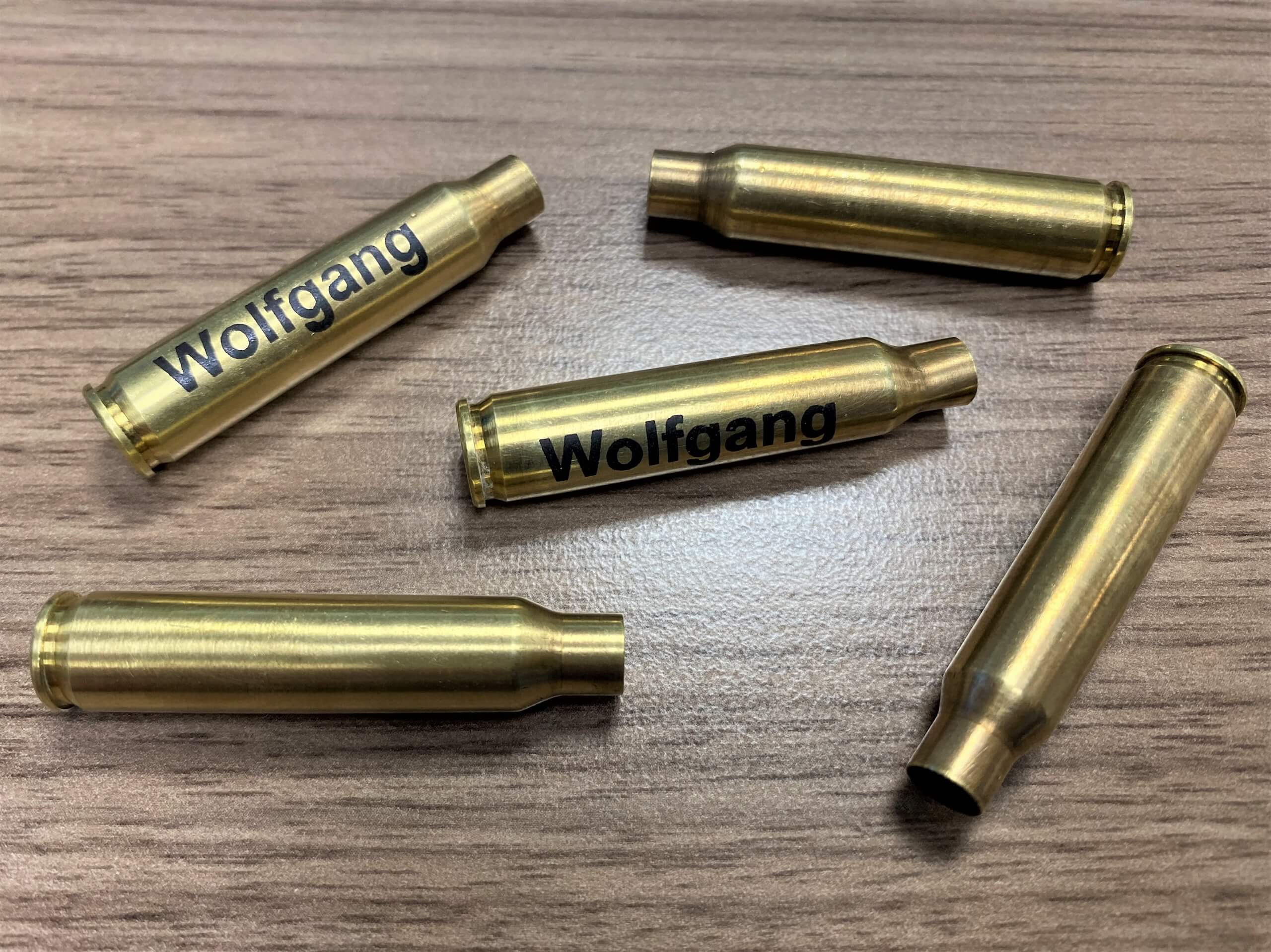 Fünf leere Messinghülsen mit dem Namen Wolfgang auf Holztisch.
