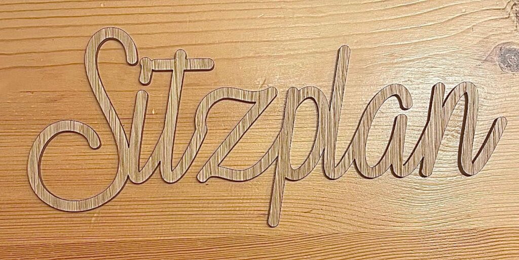 Holzschriftzug „Sitzplan“ auf Holztisch – stilvolles Dekor für Veranstaltungen oder Hochzeiten.