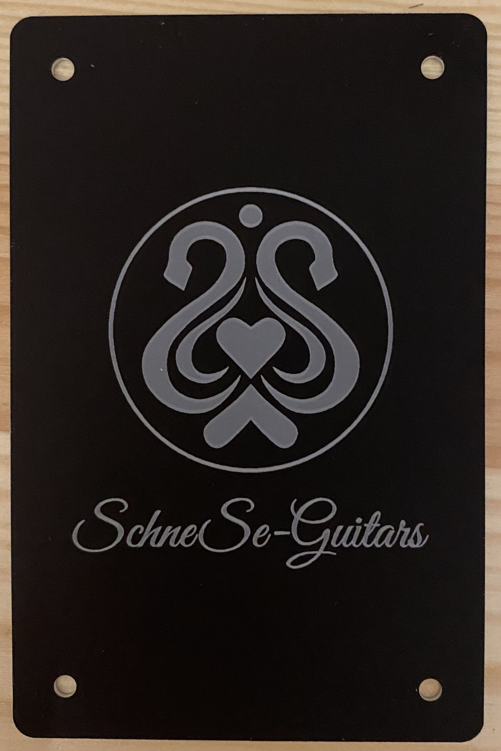Logo von SchneSe-Guitars auf dunklem Hintergrund, mit dekorativen Schnörkeln und Herzsymbol in der Mitte.
