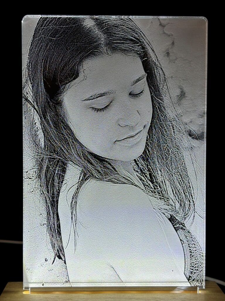 Lasergraviertes Porträt einer Person mit geschlossenen Augen auf Glasplatte, präsentiert von JMCP Lasergravuren.