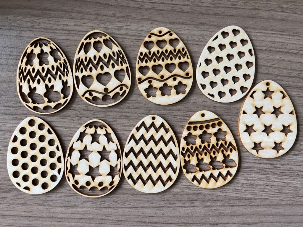 Gelaserte Holz-Eier mit Herz-, Stern- und Zickzack-Mustern auf Holztisch, ideal für personalisierte Geschenke.