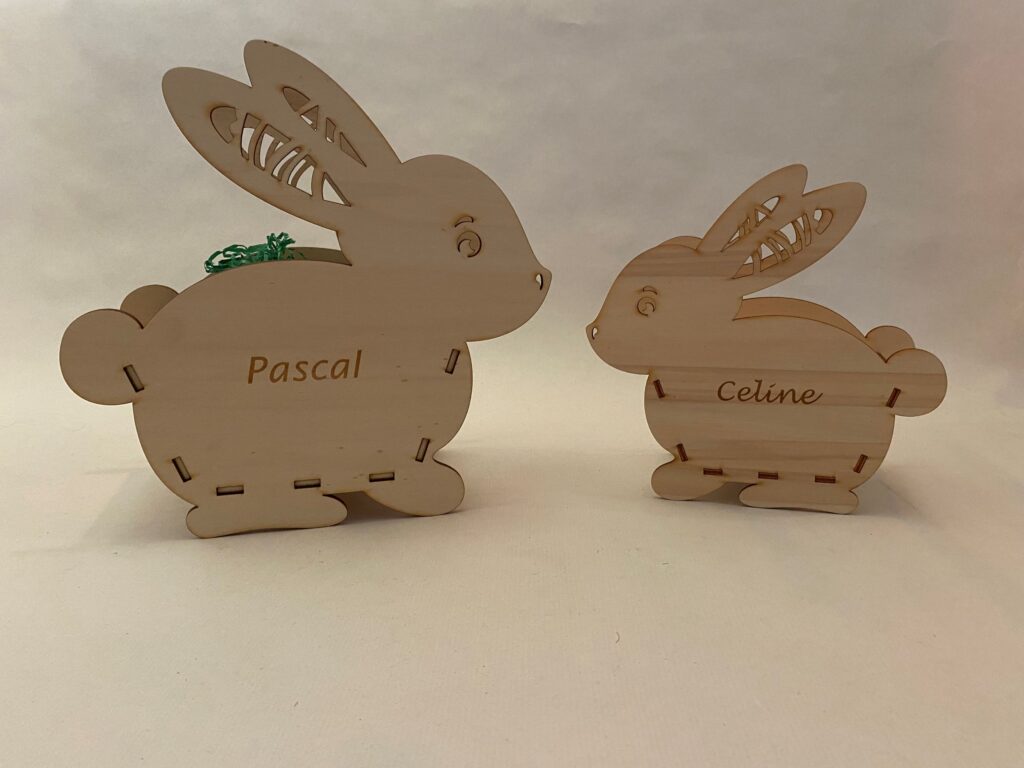 Zwei personalisierte Holzhasenfiguren mit eingravierten Namen Pascal und Celine, ideal für individuelle Geschenke.