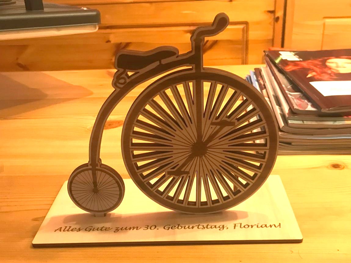 Holzkunst in Form eines klassischen Fahrrads mit Geburtstagswunsch für einen 30. Geburtstag auf Holzunterlage.