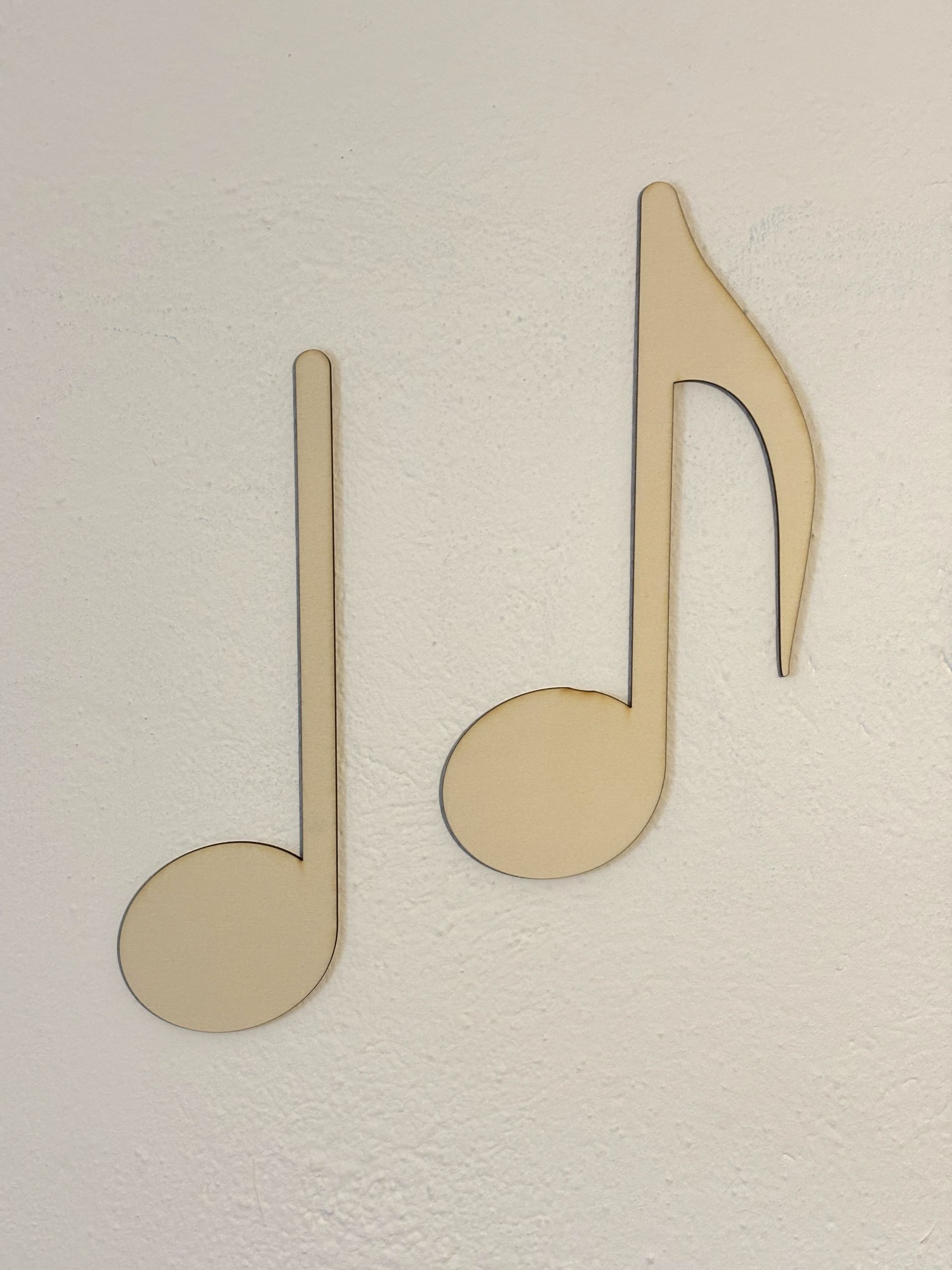 Noten aus Holz als Wanddekoration auf einer weißen Fläche. Minimalistischer Musikstil und Dekor.