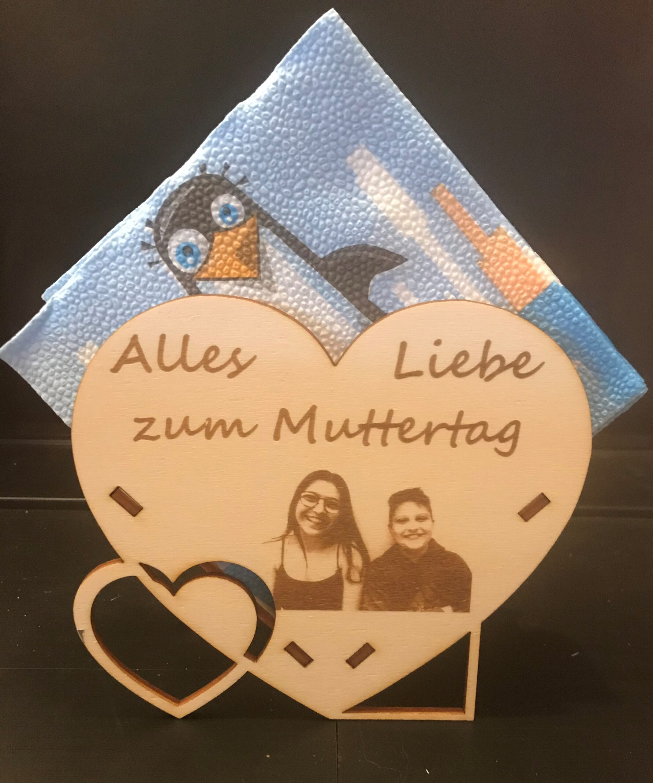 Herzförmige Muttertagskarte mit Foto und blauer Serviette im Hintergrund.