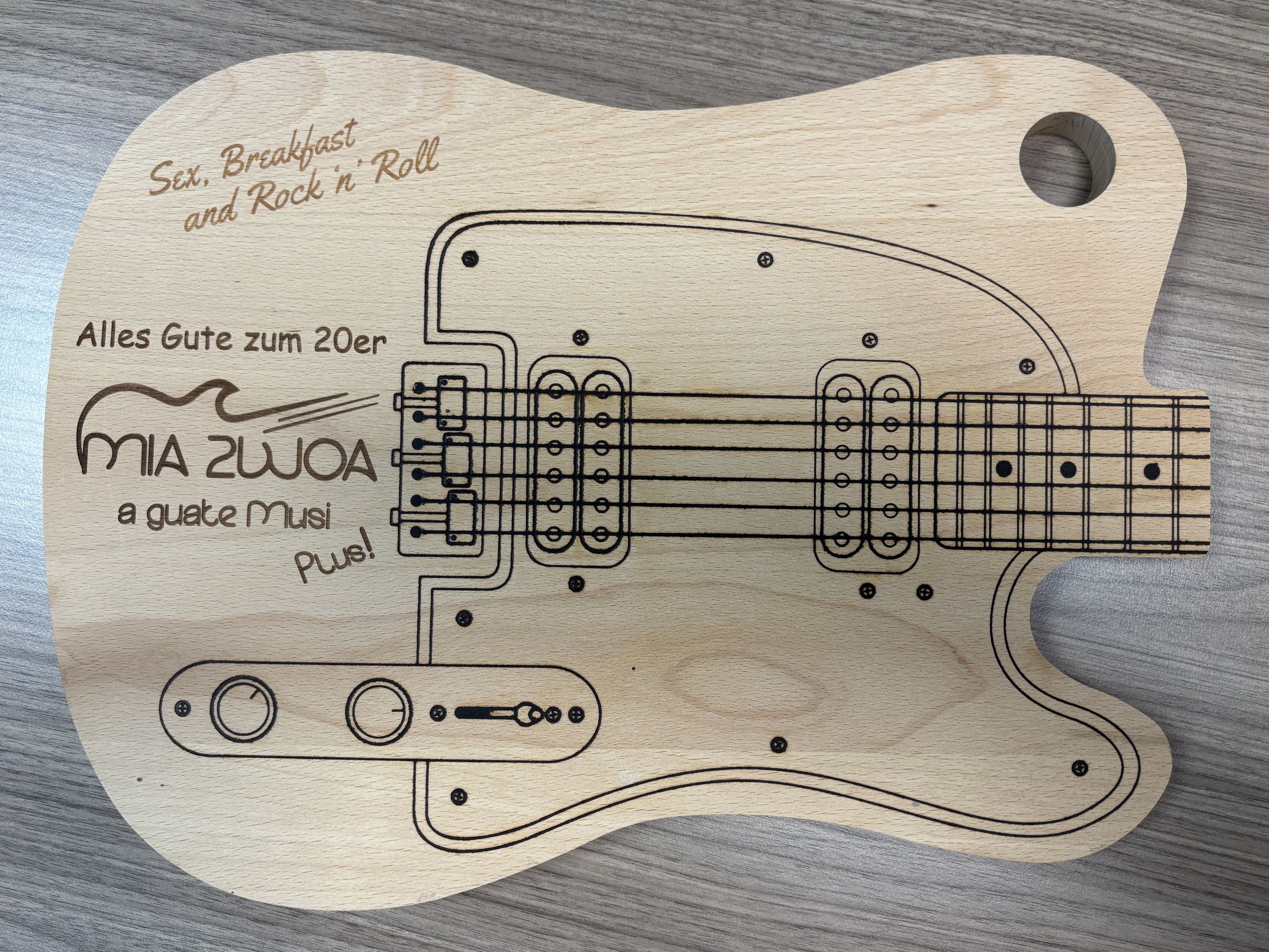 Holzbrett in Gitarrenform mit Gravur Alles Gute zum 20er, symbolisiert Musik und Feierlichkeit.