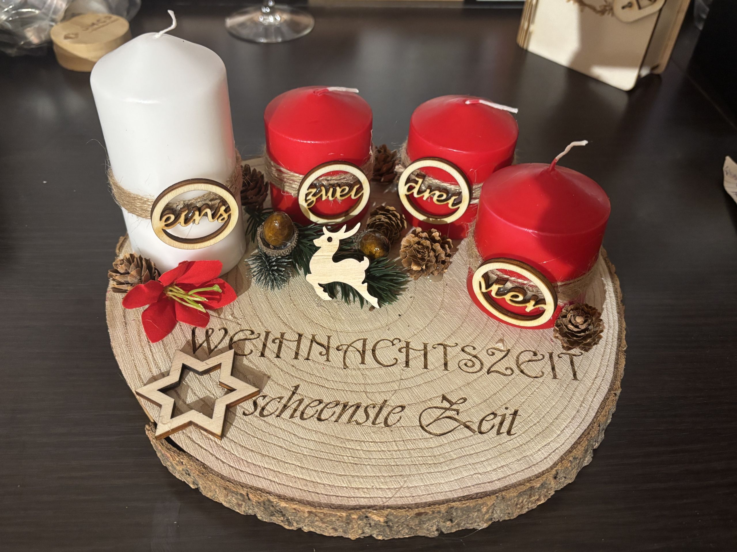 Adventskranz mit vier Kerzen auf Holzscheibe, weihnachtlich verziert und graviert mit Schriftzug Weihnachtszeit schönste Zeit.