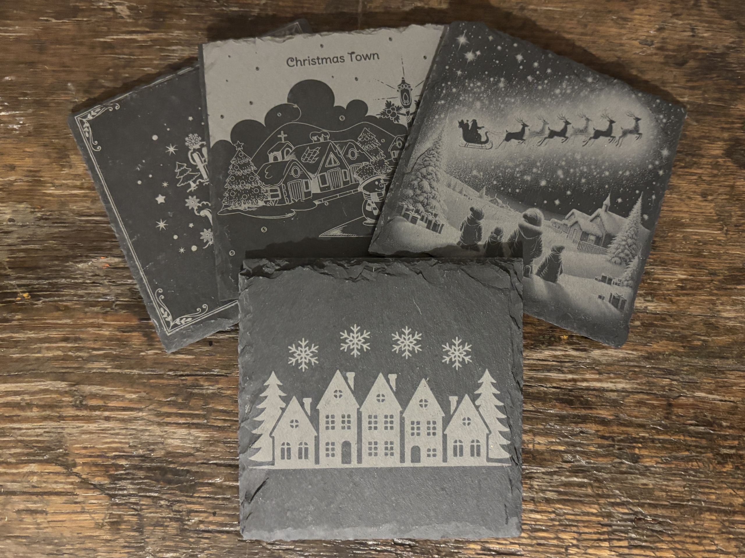 Gravierte Schieferuntersetzer mit weihnachtlichen Motiven, ideal für personalisierte Geschenke von JMCP Lasergravuren.