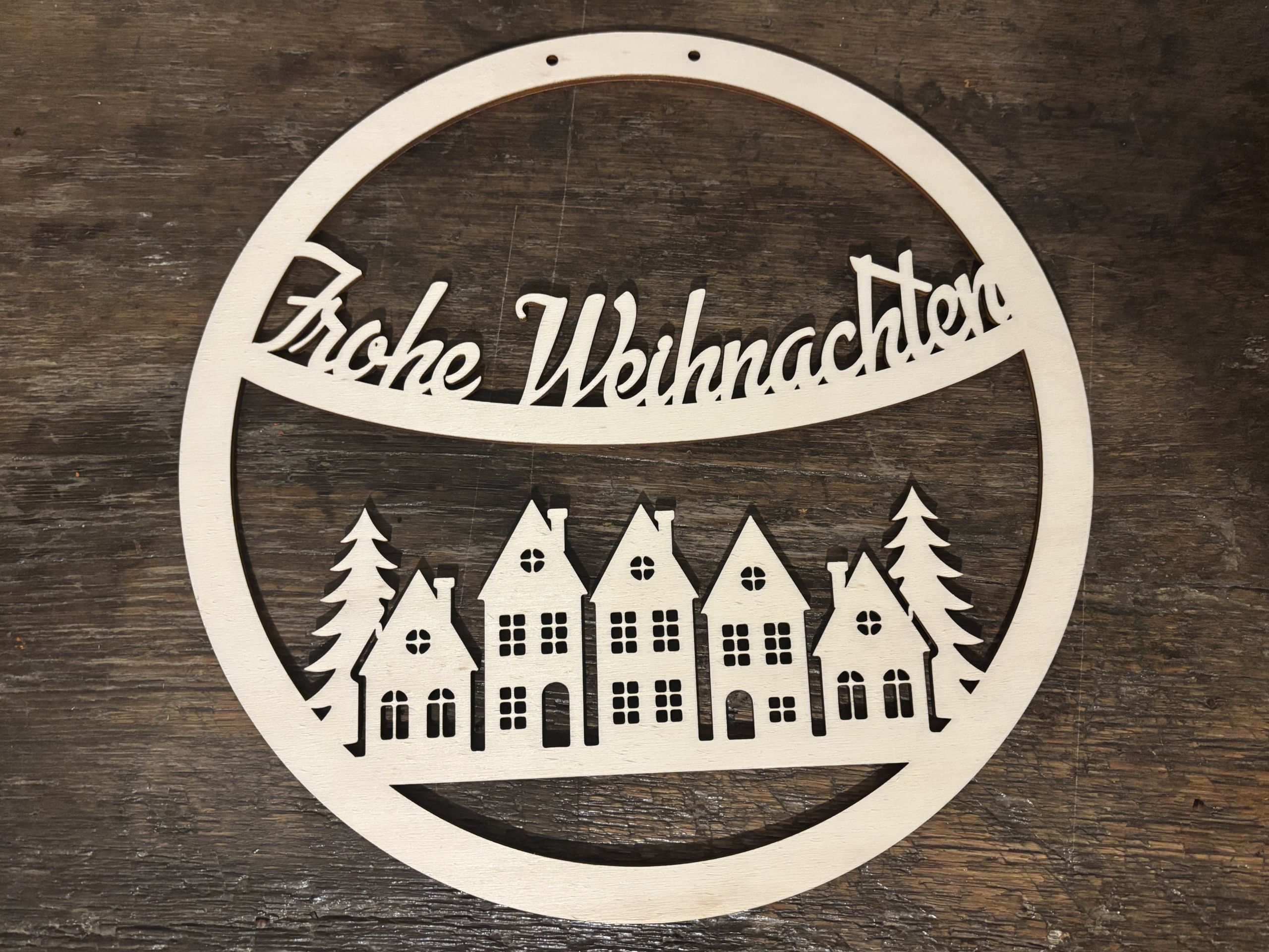 Runde Holzdeko mit Frohe Weihnachten, Häusern und Bäumen, lasergraviert für personalisierte Geschenke.